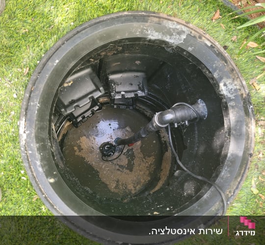 צינור שחור בתוך בור מים עם חיבורים